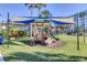 Community playground with shade sail on lush green lawn, perfect for young children at 10215 Regal Dr # 41, Largo, FL 33774