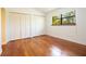 Bedroom with hardwood floors, large window, and closet with bi-fold doors at 12140 Capri S Cir, Treasure Island, FL 33706