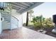 Brick patio with a spiral staircase with green shrubbery, grass and palm trees in the background at 12140 Capri S Cir, Treasure Island, FL 33706