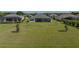 A spacious backyard with well-maintained lawn, mature trees, and a charming view of neighboring houses at 13805 Carryback Dr, Dade City, FL 33525