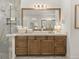 Modern bathroom vanity with sleek countertop, wooden cabinets, large mirror, and tiled shower with glass door at 13805 Carryback Dr, Dade City, FL 33525