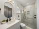 Bright bathroom featuring a marble-tiled shower with matte black fixtures, oval mirror, and white vanity at 13805 Carryback Dr, Dade City, FL 33525