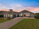 Beautifully designed home featuring a manicured lawn, stone accents, and a spacious three-car garage at 13805 Carryback Dr, Dade City, FL 33525