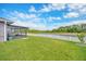 Beautiful backyard with a white picket fence, green lawn, lake view, and screened-in lanai, perfect for outdoor living at 14417 Barley Field Dr, Wimauma, FL 33598