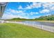 Scenic backyard features a lush green lawn, pristine white picket fence, and tranquil water views, perfect for relaxation at 14417 Barley Field Dr, Wimauma, FL 33598