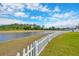 Scenic backyard view featuring lush green grass, a white picket fence, and a serene waterway at 14417 Barley Field Dr, Wimauma, FL 33598