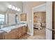 Well-lit bathroom with double sink vanity, wood cabinets, and open access to the main bedroom at 14417 Barley Field Dr, Wimauma, FL 33598