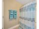 Well-lit bathroom featuring blue accent towels, a shower with a blue curtain and tile flooring at 14417 Barley Field Dr, Wimauma, FL 33598