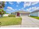 Charming home featuring a well-manicured lawn, clean driveway, and a two-car garage, set beneath a bright, cloudy sky at 14417 Barley Field Dr, Wimauma, FL 33598