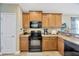 Well-equipped kitchen featuring wooden cabinets, granite countertops, and modern black appliances at 14417 Barley Field Dr, Wimauma, FL 33598