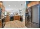 Well-equipped kitchen with stainless steel fridge, wood cabinets, and open layout to dining area at 14417 Barley Field Dr, Wimauma, FL 33598
