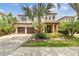 Charming two-story home featuring a two-car garage, lush landscaping, and a beautiful palm tree in the front yard at 20347 Chestnut Grove Dr, Tampa, FL 33647