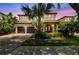 Charming two-story home featuring a two-car garage, lush landscaping, and a beautiful palm tree in the front yard at 20347 Chestnut Grove Dr, Tampa, FL 33647