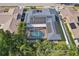 Aerial view of a house with solar panels and screened-in pool surrounded by lush greenery at 206 Timberview Dr, Safety Harbor, FL 34695