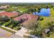 Aerial view showcasing the property's tile roof, landscaping, and scenic pond in a lush environment at 218 Pesaro Dr, North Venice, FL 34275