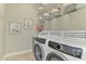 Laundry room with front load washer and dryer, wire shelves, and decorative artwork at 218 Pesaro Dr, North Venice, FL 34275