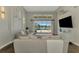 Comfortable living room with a plush sofa, a TV, and a large window overlooking the screened pool at 218 Pesaro Dr, North Venice, FL 34275