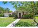 Charming single-story home with a well-manicured lawn, lush landscaping, and decorative shutters and front door at 219 Park S Cir, Dunedin, FL 34698