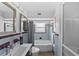 Bright bathroom with double vanity mirror, a bathtub, and shower with decorative blue and burgundy tiling at 222 N Clearview Ave, Tampa, FL 33609