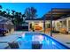A well-lit backyard featuring a pool with built-in seating, a covered lounge area, and backyard fire pit at 222 N Clearview Ave, Tampa, FL 33609