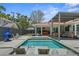 An expansive pool area with in-pool seating, outdoor lounge, and a glimpse into the adjacent bedroom at 222 N Clearview Ave, Tampa, FL 33609