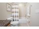 Neutral bathroom features a shower-tub combo with a shower curtain, toilet, wall art, and tile flooring at 2527 Silverback Ct, Palm Harbor, FL 34684