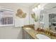 Bathroom featuring a granite countertop, double sinks, gold fixtures, and decorative wall art at 3176 Duane Ave, Oldsmar, FL 34677
