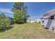 Spacious backyard with a green lawn, mature trees, sheds, and a clothesline, perfect for outdoor activities at 35128 Dale Ave, Zephyrhills, FL 33541