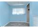 A blue bedroom featuring a large window, gray flooring, and ample closet space at 35128 Dale Ave, Zephyrhills, FL 33541
