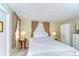 Bright bedroom featuring neutral decor, two windows with drapes, side tables with lamps and a white storage cabinet at 35128 Dale Ave, Zephyrhills, FL 33541