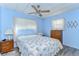 Bright bedroom with a floral comforter, side tables, dresser and a ceiling fan with a window at 35128 Dale Ave, Zephyrhills, FL 33541