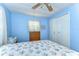 Cozy bedroom with blue walls, floral bedding, closet, dresser, and a ceiling fan for added comfort at 35128 Dale Ave, Zephyrhills, FL 33541