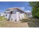View of house showing white siding, pink trim, grassy lawn, tree and an AC unit at 35128 Dale Ave, Zephyrhills, FL 33541