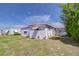 Angle view of a single-story home showing white siding, pink trim, and a well-kept lawn with tree at 35128 Dale Ave, Zephyrhills, FL 33541