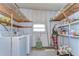 Functional laundry room with washer, dryer, shelving for storage, and a bright window for natural light at 35128 Dale Ave, Zephyrhills, FL 33541