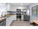 Well-equipped kitchen with stainless steel appliances, granite countertops, white cabinetry, and a hardwood floor at 3600 Magnolia Ridge Cir # 1221-G, Palm Harbor, FL 34684