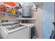 Laundry room with modern washer and dryer, water heater, and storage shelves filled with laundry products at 3600 Magnolia Ridge Cir # 1221-G, Palm Harbor, FL 34684