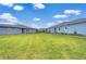 Large backyard with green lawn, light-blue painted home exteriors, and blue skies with white clouds at 3765 Maxwell Park Dr, Sun City Center, FL 33573