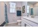 Bright bathroom with a single sink vanity, white countertop, gray tiled floor, toilet, and shower with colorful curtain at 3765 Maxwell Park Dr, Sun City Center, FL 33573