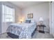 Bright bedroom features a queen-size bed with blue floral bedding, window with blinds, and side tables with lamps at 3765 Maxwell Park Dr, Sun City Center, FL 33573