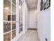 Hallway with glass paneled doors, a light gray tiled floor, white walls, and several framed photos on the wall at 3765 Maxwell Park Dr, Sun City Center, FL 33573