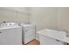 Bright laundry room with modern washer, dryer, utility sink, and wire shelving at 4500 Fieldview Cir, Wesley Chapel, FL 33545