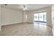 Open living room with ceramic tile flooring and sliding door to screened patio at 4500 Fieldview Cir, Wesley Chapel, FL 33545