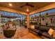 Covered patio featuring comfortable seating and hanging plants, overlooking a peaceful backyard with a view of the lake at 4719 Tramanto Ln, Wesley Chapel, FL 33543