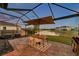 Screened-in lanai with patio furniture overlooking a tranquil water view, perfect for outdoor relaxation and entertaining at 4719 Tramanto Ln, Wesley Chapel, FL 33543