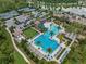 Aerial view of a beautiful community pool with slides, a tower, lounge chairs, palm trees, and a tennis court at 4719 Tramanto Ln, Wesley Chapel, FL 33543