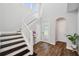 Bright entryway showcasing dark hardwood floors, a staircase, and an arched doorway at 4719 Tramanto Ln, Wesley Chapel, FL 33543