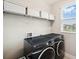 Efficient laundry room with modern washer and dryer, and upper storage shelves at 4719 Tramanto Ln, Wesley Chapel, FL 33543