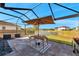 Screened-in patio featuring a dining table with an umbrella, lake views, and stylish stone flooring at 4719 Tramanto Ln, Wesley Chapel, FL 33543