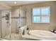 Bathroom featuring a soaking tub, tile surround, glass shower and plantation shutters at 4744 Wandering Way, Wesley Chapel, FL 33544